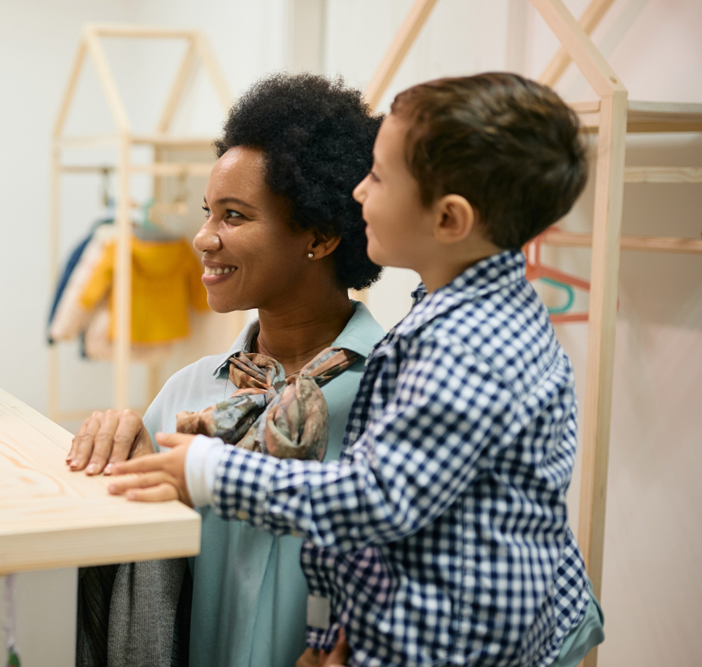 A teacher and a young boy are smiling together as they look at something, sharing a moment of connection and engagement.