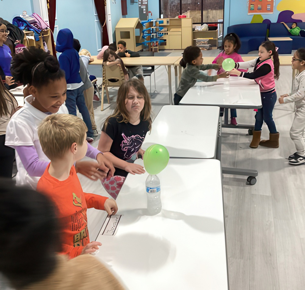 Children engage in a fun science experiment, laughing and excitedly interacting with balloons and water bottles.
