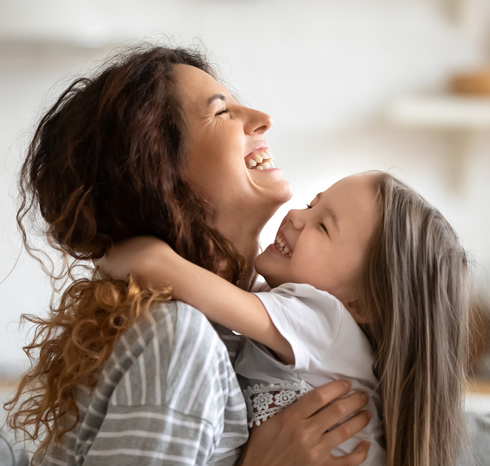 A joyful moment captures a teacher and her student, both laughing and expressing happiness.