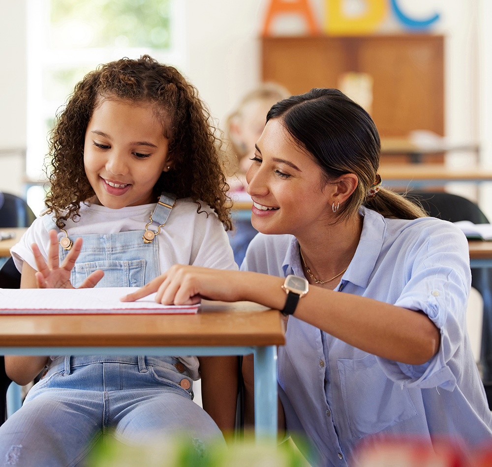 The girl appears to be excited as she shares something, while the teacher shows encouragement and support.